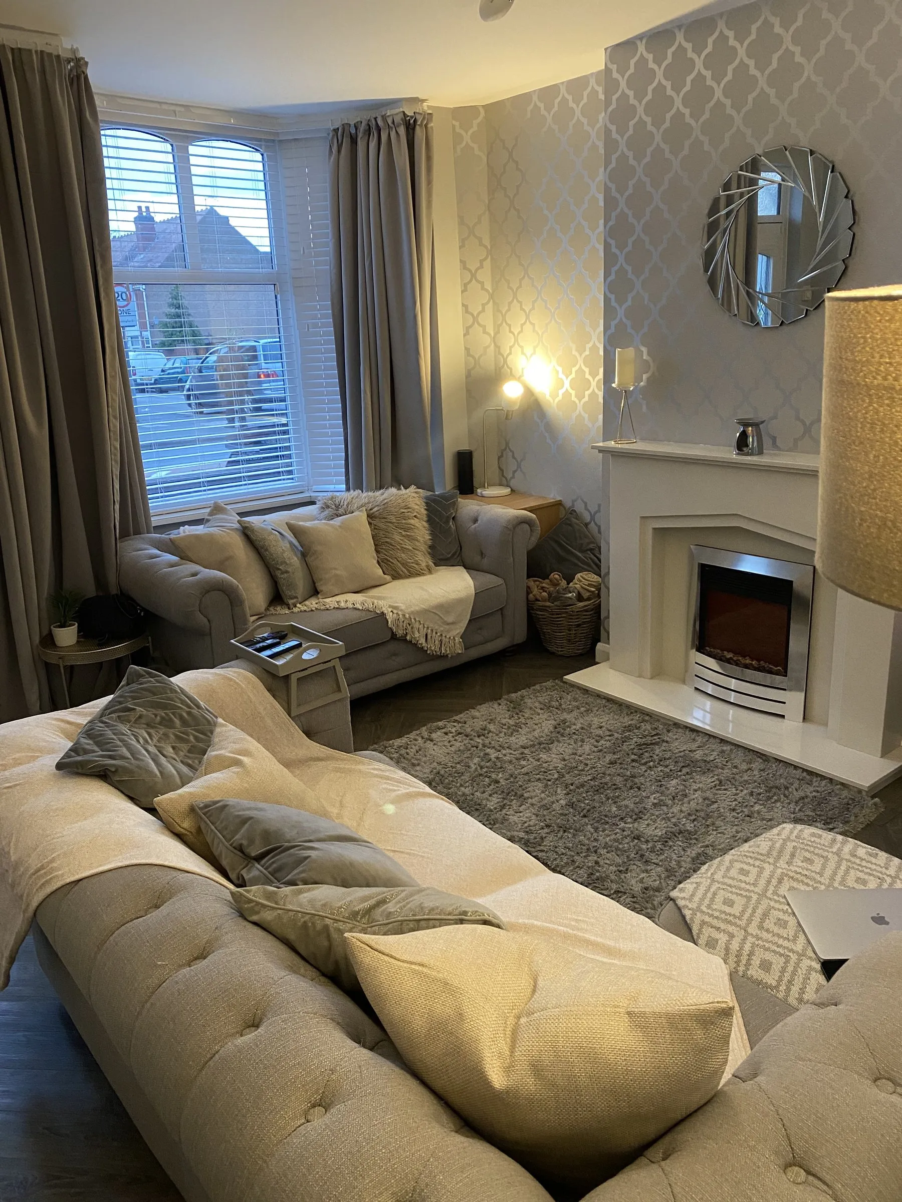 A cosy grey and cream living room with a lit fireplace
