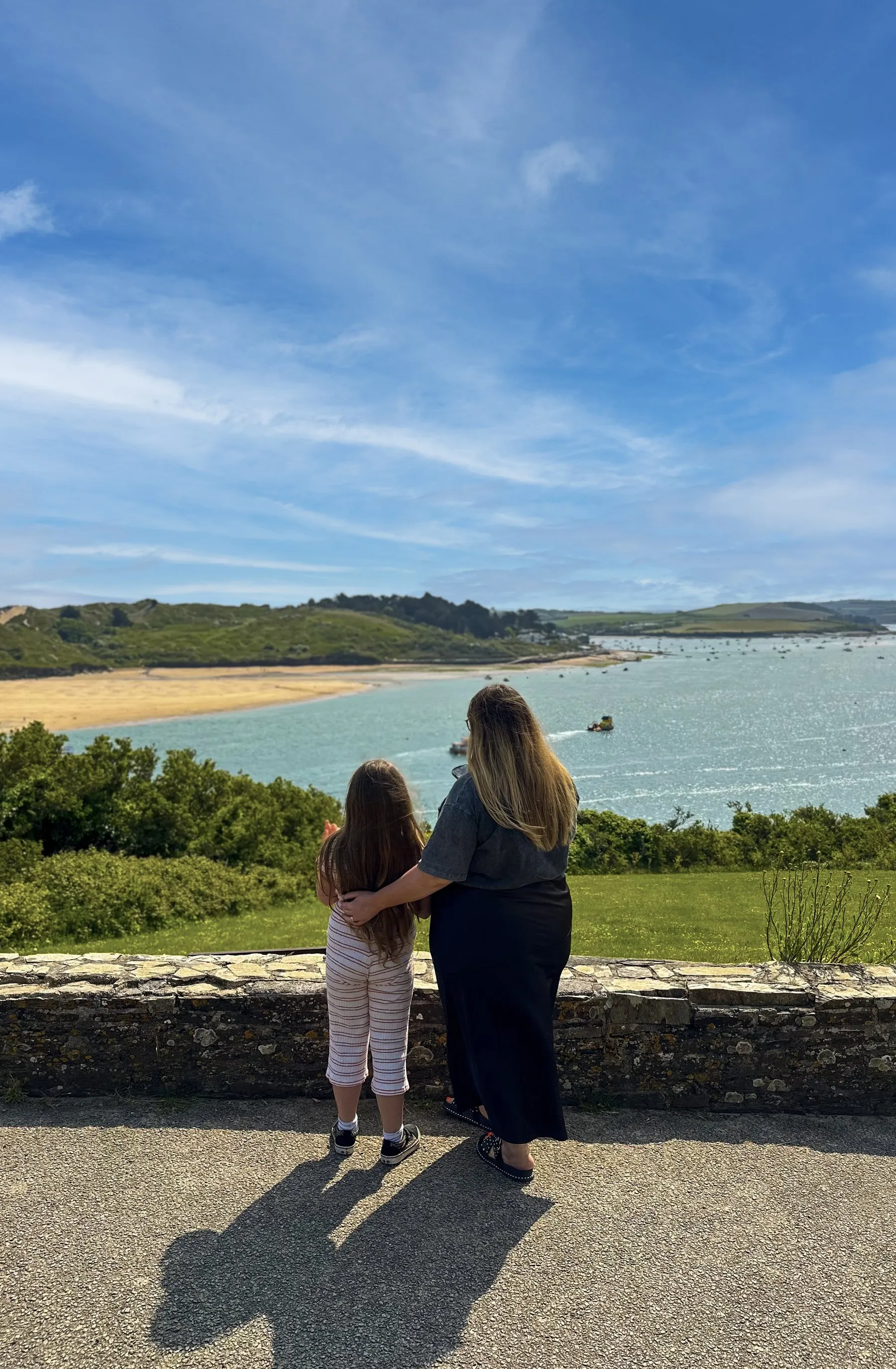A mother and daughter looking out over a coastal estuary